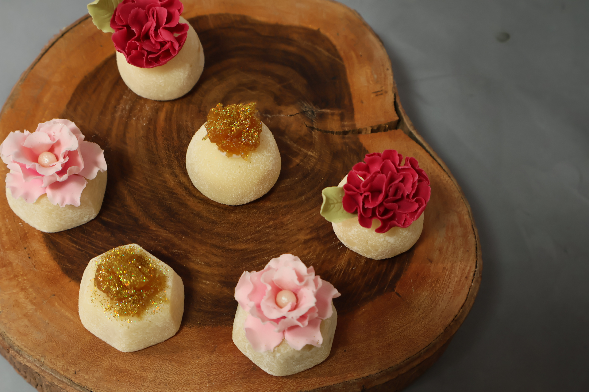 Brigadeiros de abacaxi com coco sobre tábua de madeira.